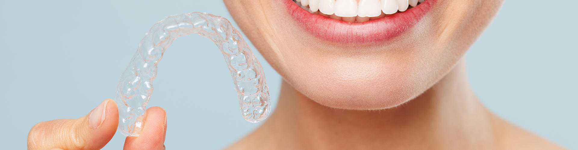 smiling woman holding clear aligner